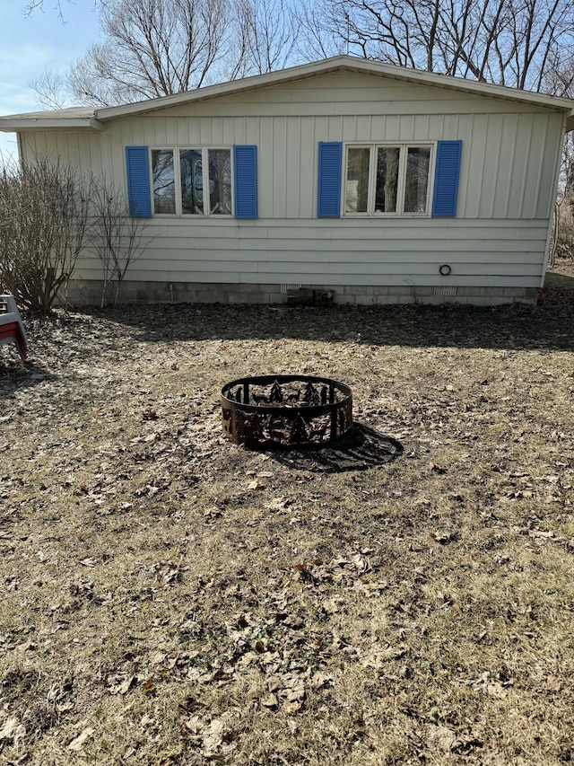 rear view of property with board and batten siding and an outdoor fire pit