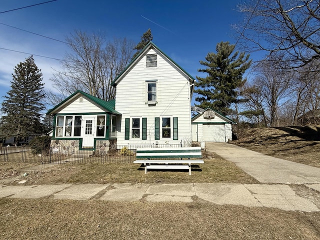 back of house with a fenced front yard, an outbuilding, a garage, and driveway