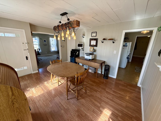 dining space featuring baseboards, wood finished floors, and vaulted ceiling