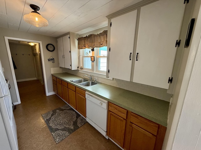 kitchen featuring white dishwasher, a sink, dark floors, brown cabinets, and backsplash