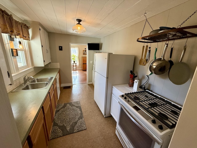 kitchen with a sink, white appliances, wooden ceiling, and light countertops