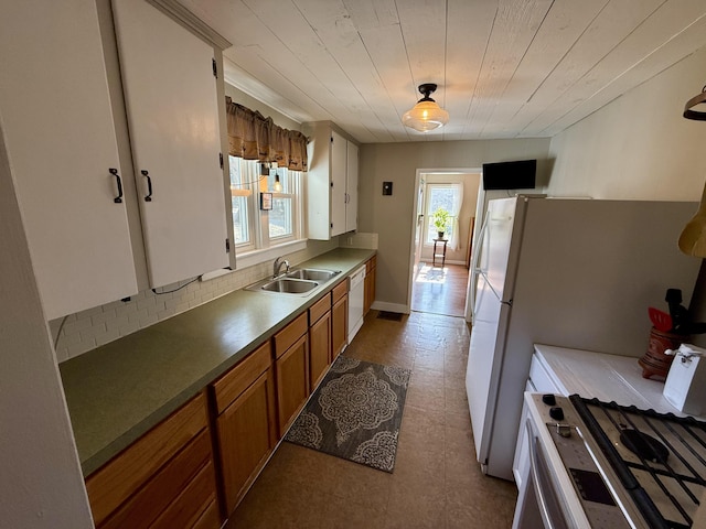 kitchen featuring tile patterned floors, a sink, tasteful backsplash, white appliances, and brown cabinetry