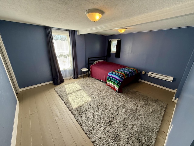 bedroom with baseboards, a textured ceiling, and wood finished floors