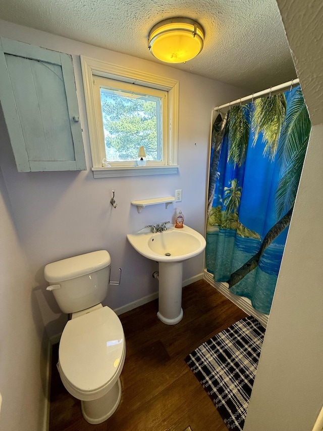 bathroom with curtained shower, baseboards, a textured ceiling, and wood finished floors