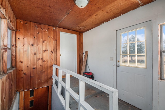 doorway to outside with wooden walls and wooden ceiling