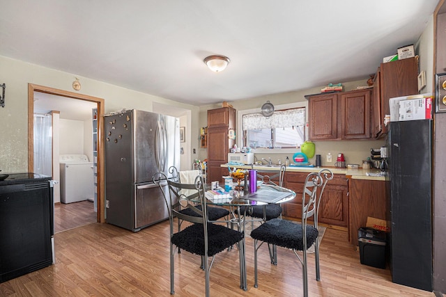 kitchen featuring white microwave, light wood finished floors, washer / dryer, freestanding refrigerator, and light countertops