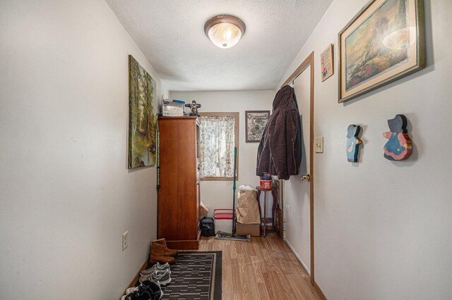 corridor featuring a textured ceiling and light wood-type flooring