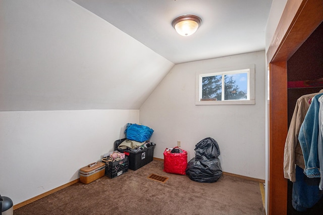 interior space with vaulted ceiling, visible vents, baseboards, and carpet floors