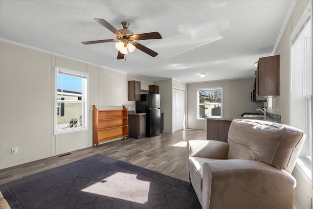 living room featuring ornamental molding, ceiling fan, a healthy amount of sunlight, and wood finished floors