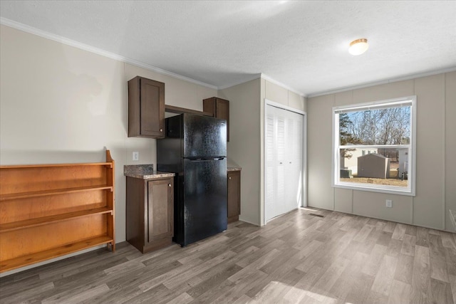 kitchen featuring a textured ceiling, freestanding refrigerator, light wood-style floors, and ornamental molding