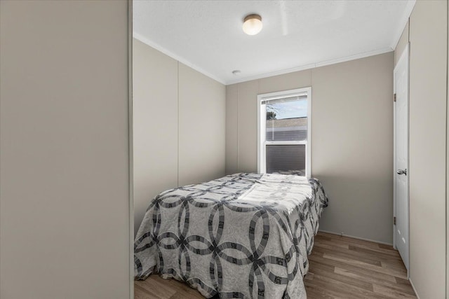 bedroom with wood finished floors and ornamental molding