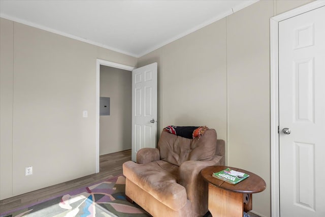 sitting room with electric panel, ornamental molding, and wood finished floors