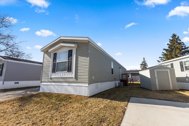 view of home's exterior featuring cooling unit, a lawn, an outdoor structure, and a shed