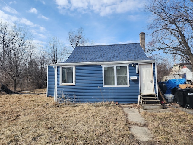 view of front of home with a shingled roof, a chimney, and entry steps