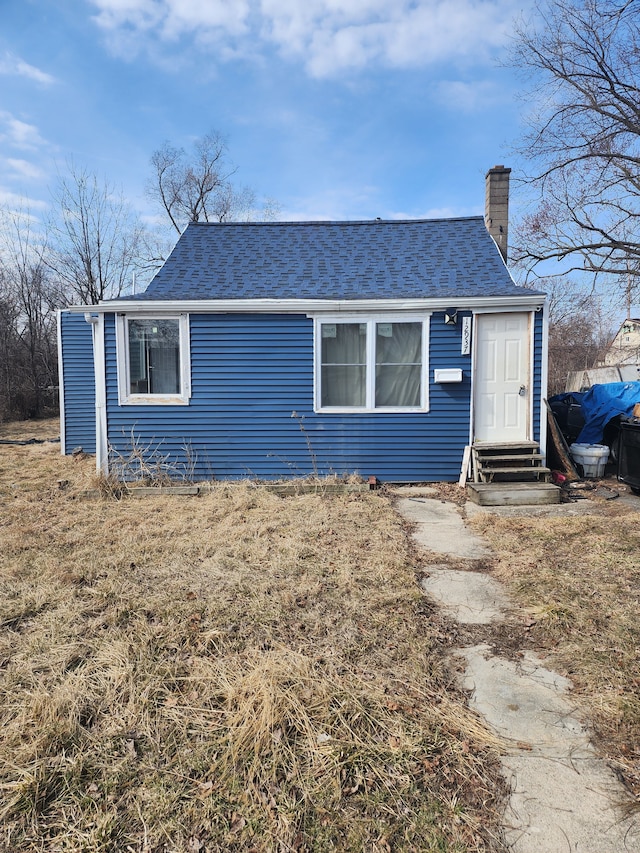 view of front of home featuring entry steps, a shingled roof, and a chimney