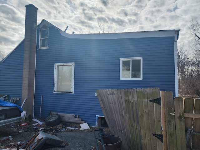 view of home's exterior with a chimney and fence