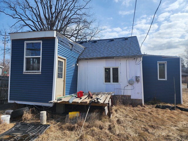 rear view of property with an outdoor structure and a shingled roof