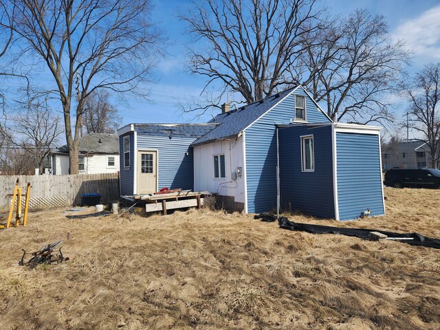 rear view of property featuring a chimney and fence