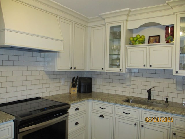 kitchen featuring stainless steel electric range oven, custom exhaust hood, a sink, crown molding, and tasteful backsplash