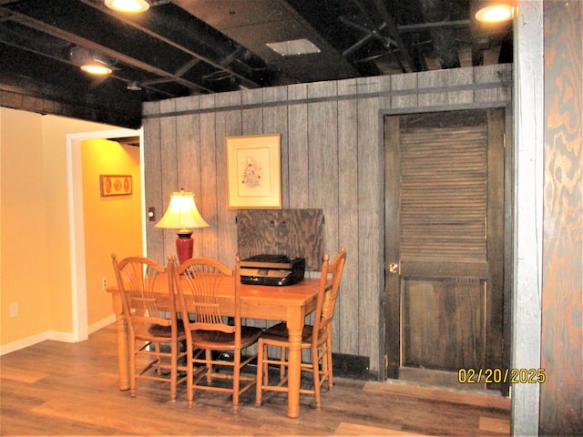 dining space with wooden walls, wood finished floors, and baseboards