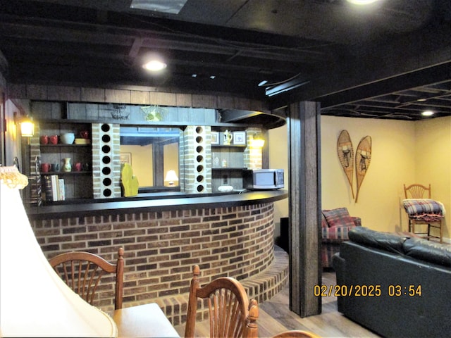 bar with stainless steel microwave, a dry bar, and wood finished floors