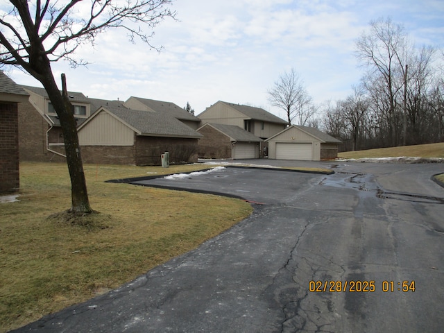 view of front facade featuring a front lawn, brick siding, and a garage