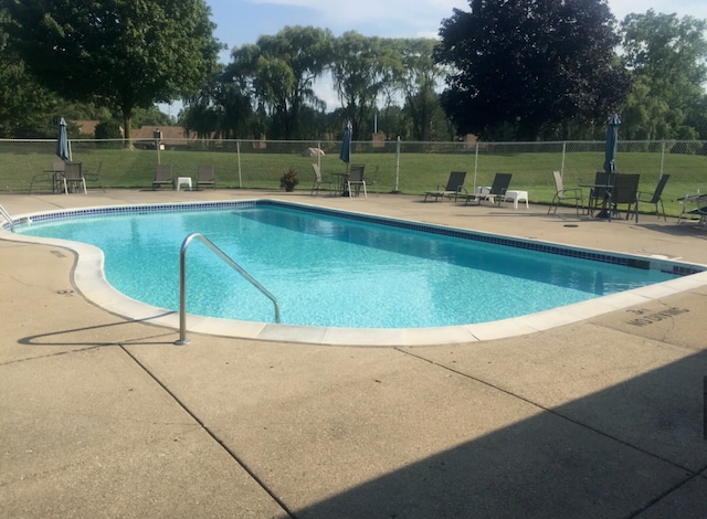 community pool featuring a patio, a lawn, and fence