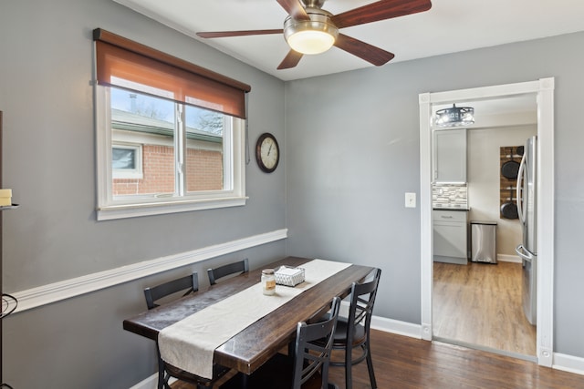 dining space featuring dark wood-type flooring, a ceiling fan, and baseboards