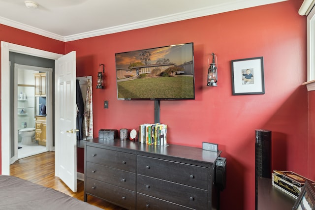 bedroom with wood finished floors, baseboards, and ornamental molding