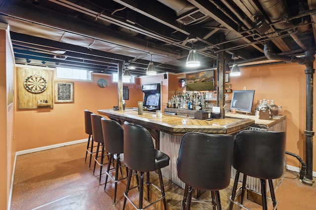 bar featuring visible vents, baseboards, a bar, and finished concrete flooring