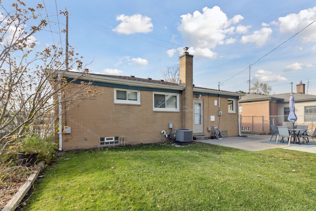 back of property featuring fence, a yard, a chimney, a patio area, and brick siding