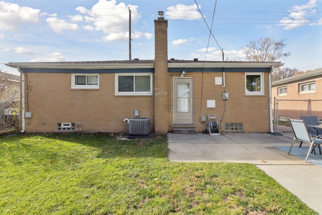 back of property featuring a yard, brick siding, central AC, and fence