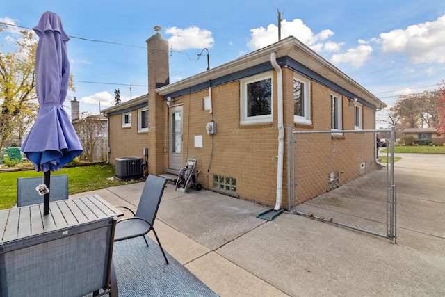 back of house with a patio, a chimney, entry steps, central air condition unit, and brick siding