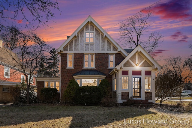 english style home with a lawn, brick siding, and a chimney