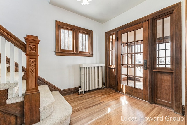 foyer with stairs, radiator heating unit, baseboards, and light wood finished floors