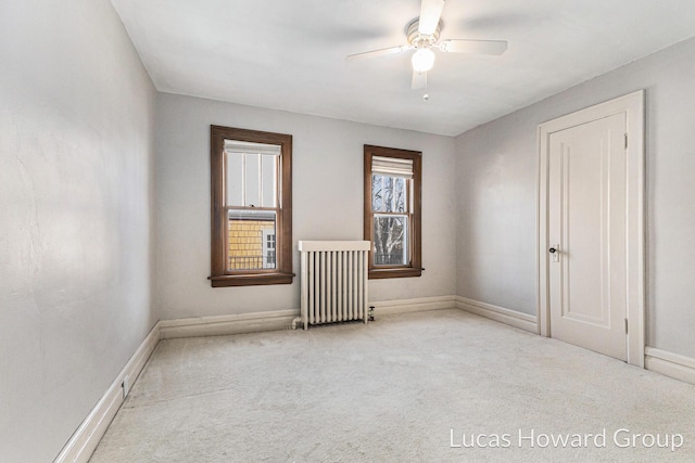 spare room with carpet flooring, radiator, baseboards, and ceiling fan