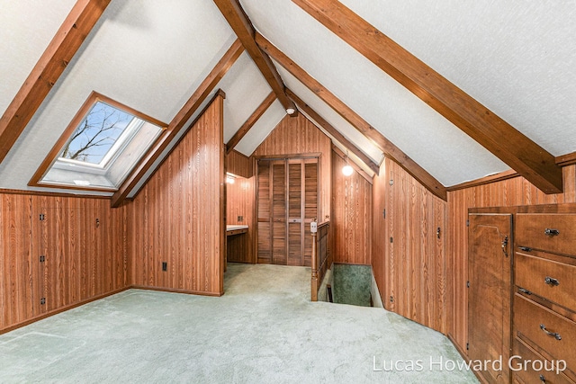 additional living space featuring vaulted ceiling with skylight, a textured ceiling, carpet floors, and wood walls