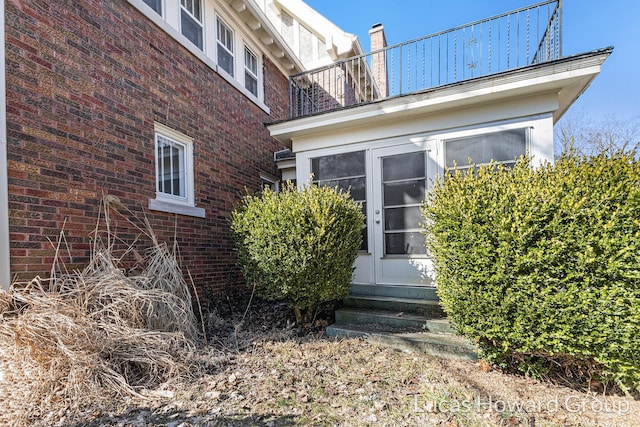 doorway to property featuring brick siding and a balcony