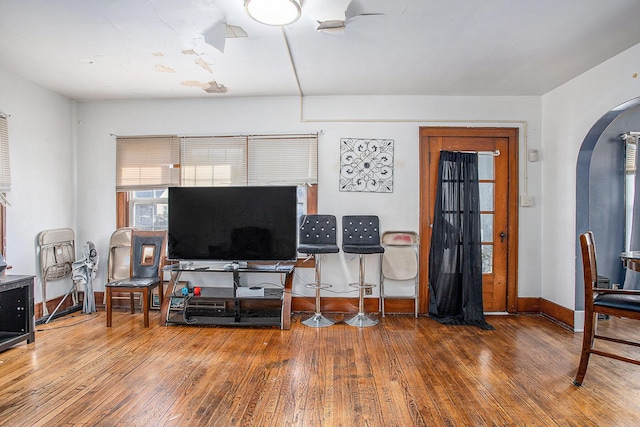 living area featuring hardwood / wood-style floors, baseboards, and arched walkways