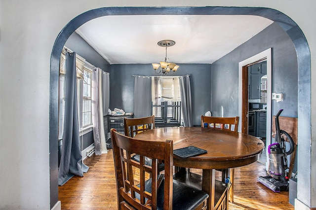 dining area featuring arched walkways, a notable chandelier, and hardwood / wood-style floors