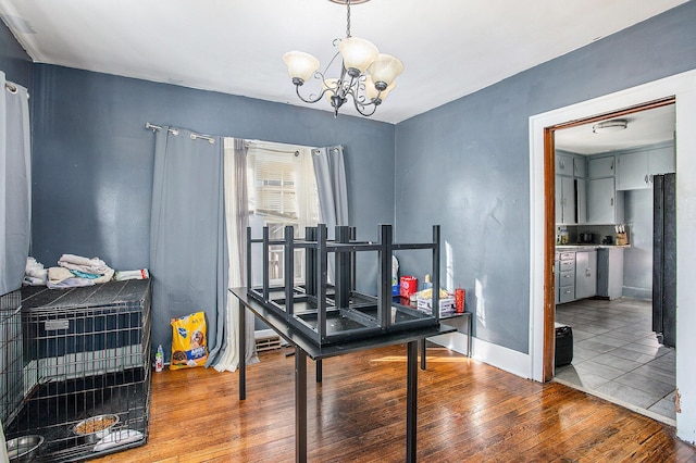 home office with baseboards, an inviting chandelier, and hardwood / wood-style flooring