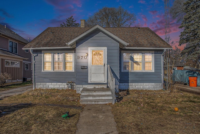 bungalow-style house featuring a chimney and a shingled roof