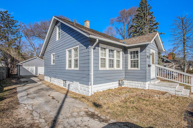 view of home's exterior with a shingled roof, fence, a chimney, a garage, and an outdoor structure