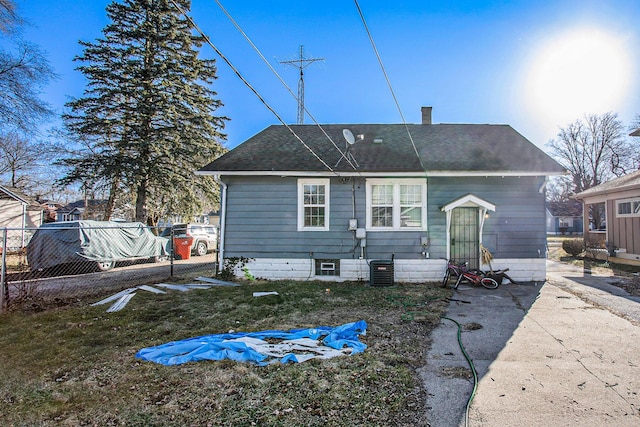 rear view of property with a shingled roof, a chimney, and fence