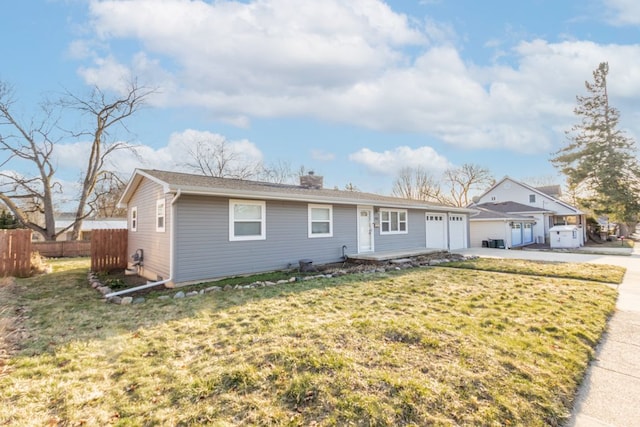 view of front facade with fence, concrete driveway, a front yard, a chimney, and an attached garage