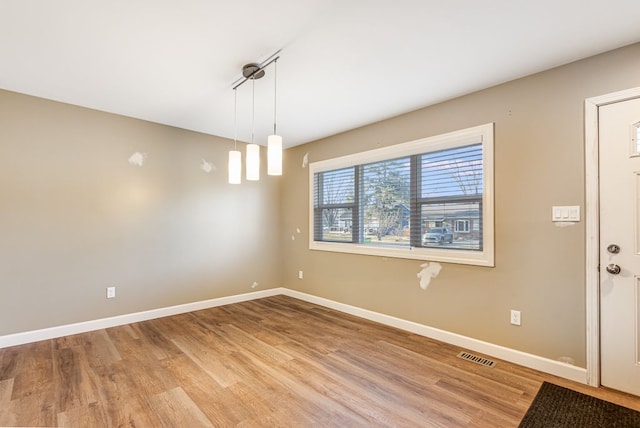 unfurnished dining area featuring light wood-type flooring, visible vents, and baseboards