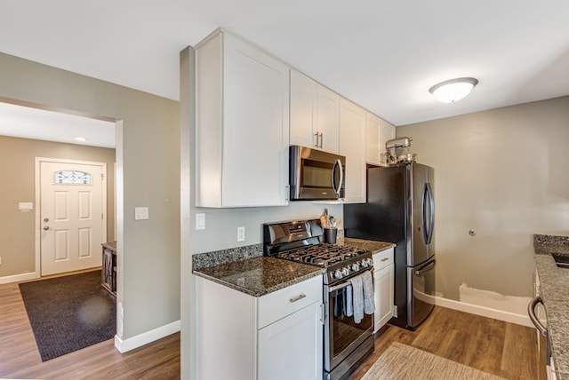 kitchen with white cabinets, wood finished floors, baseboards, and appliances with stainless steel finishes