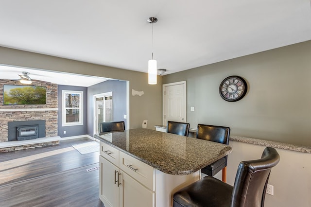 kitchen with a center island, pendant lighting, a kitchen breakfast bar, white cabinetry, and dark wood-style flooring