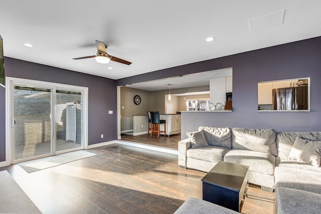 living area featuring radiator, wood finished floors, baseboards, recessed lighting, and ceiling fan