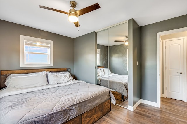 bedroom with a closet, a ceiling fan, baseboards, and wood finished floors